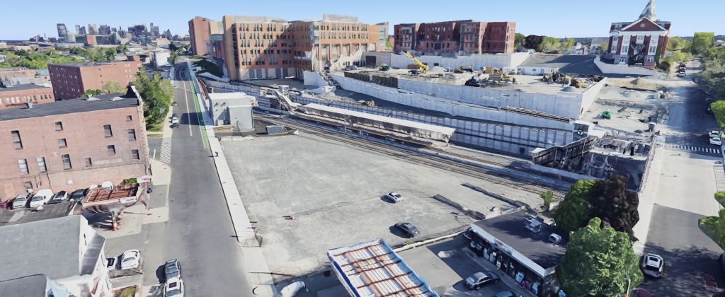 Aerial shot of the Gilman Square T Station and the adjacent gravel lot as the site for the Gilman Park project.